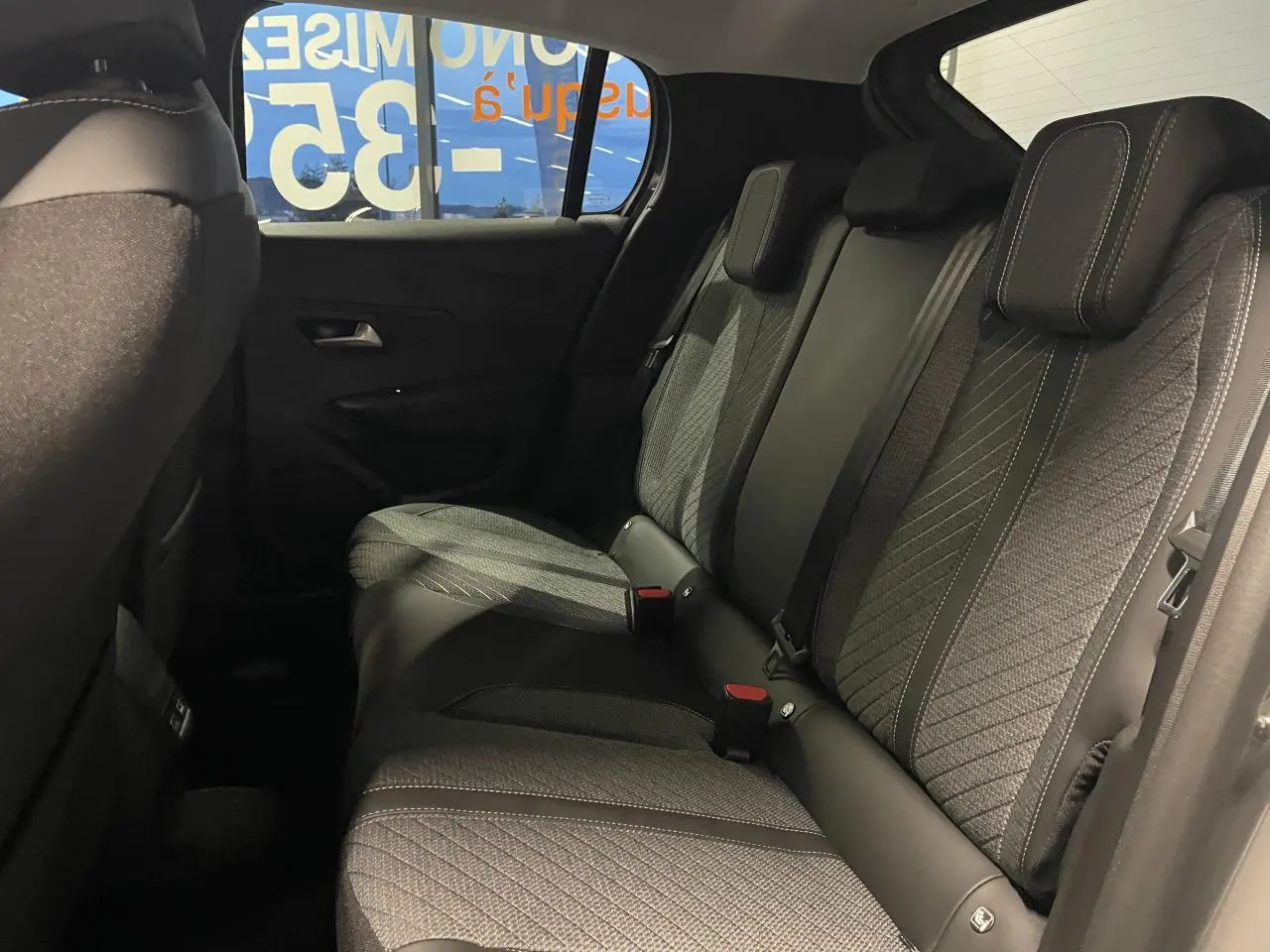 Vue latérale intérieure des sièges arrière gris foncé avec surpiqûres claires du Peugeot 208 Allure 2025.