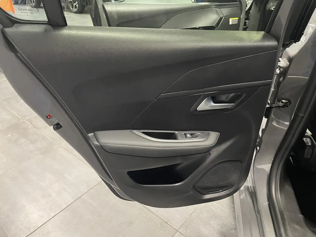 Vue rapprochée de la porte arrière gauche gris selenium de la Peugeot 208 Allure 2025 avec accoudoir et commande de lève-vitre.