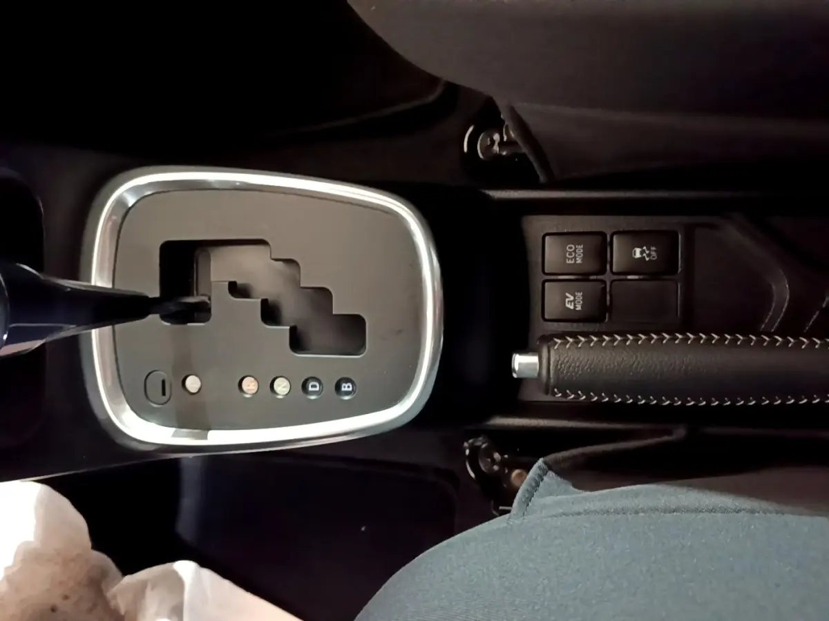 Vue rapprochée de la console centrale de la Toyota Yaris blanche, montrant la boîte automatique et le frein à main cuir noir.