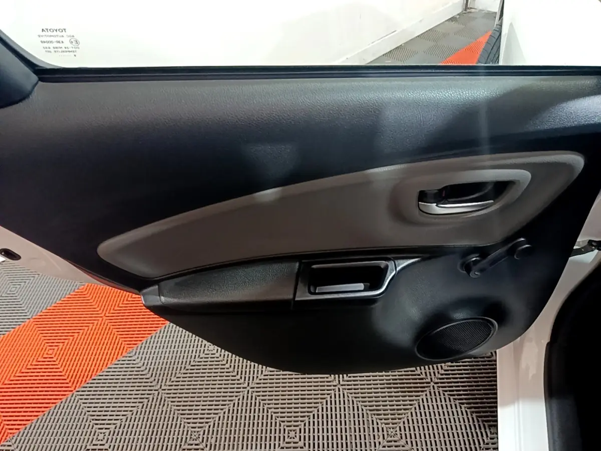 Vue rapprochée de la porte avant gauche blanche de la Toyota Yaris 2019, avec poignée intérieure et haut-parleur intégré.