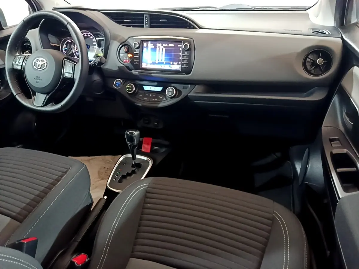 Vue intérieure avant droite de la Toyota Yaris 2019, tableau de bord noir avec écran tactile et volant cuir multifonctions.