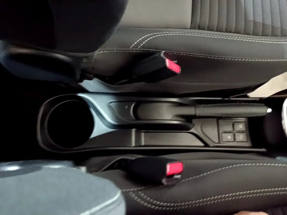 Vue plongeante sur la console centrale noire de la Toyota Yaris 2019, avec frein à main et ceintures rouges visibles.