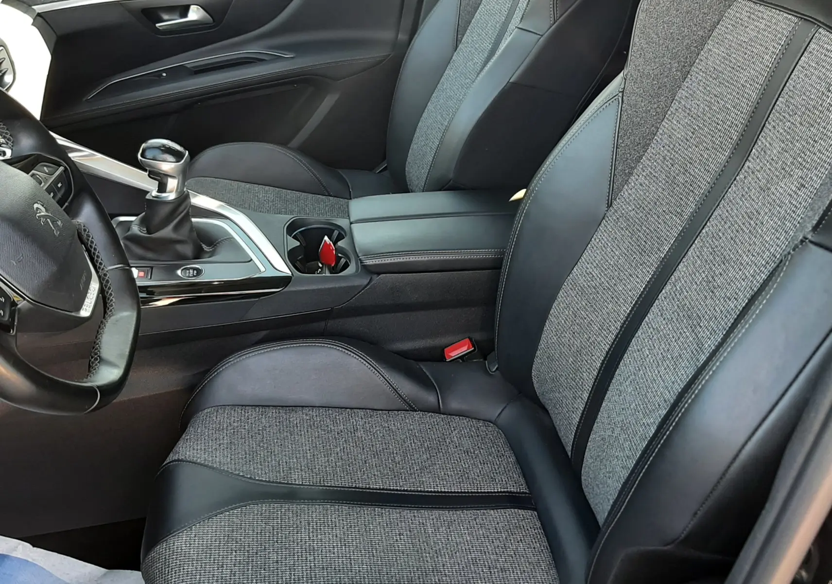 Vue intérieure côté conducteur du Peugeot 3008 noir 2019, sièges tissu et cuir bicolore avec console centrale et levier de vitesses manuel.