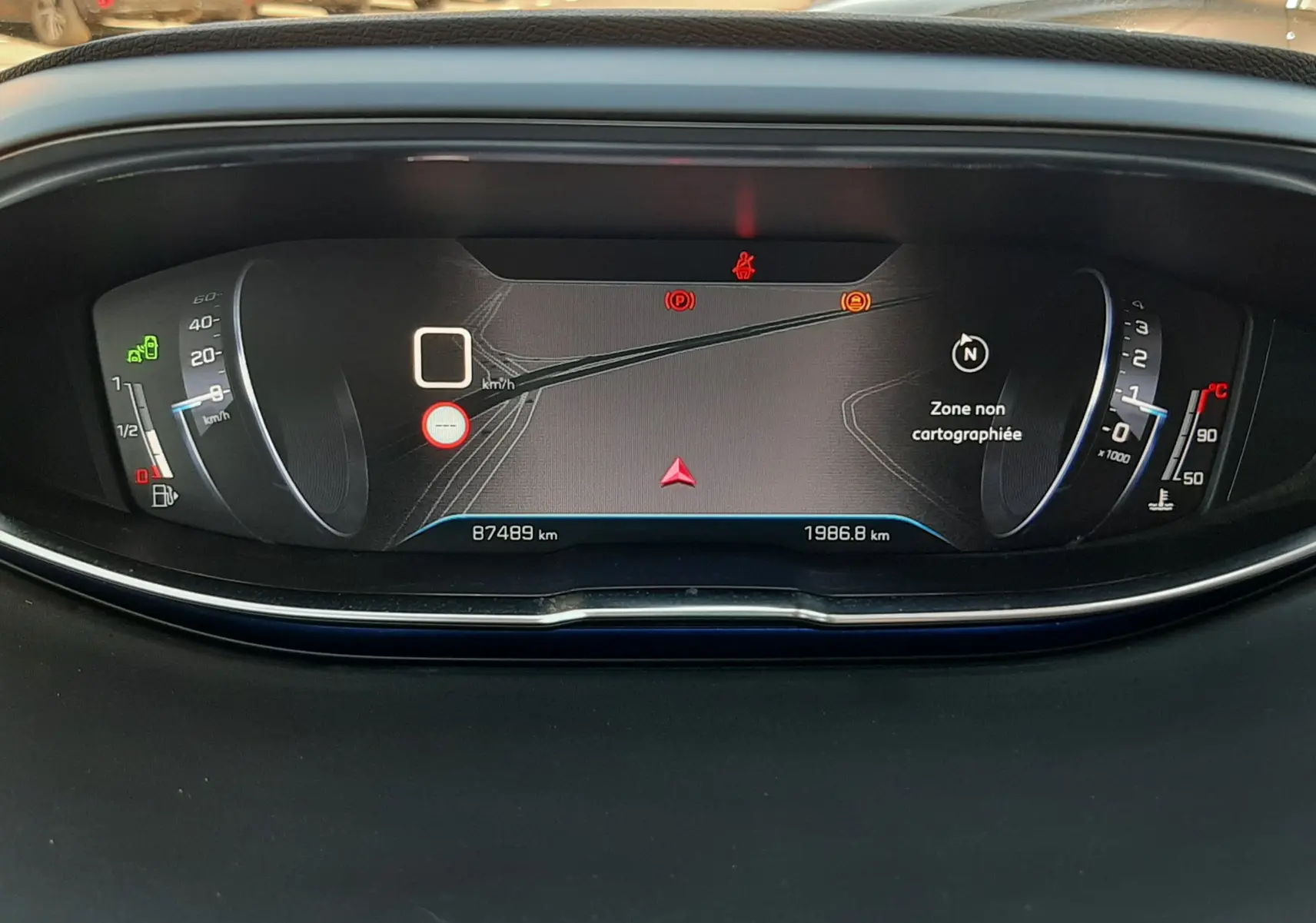 Vue rapprochée du tableau de bord numérique du Peugeot 3008 noir, affichant la navigation et les voyants d'alerte.