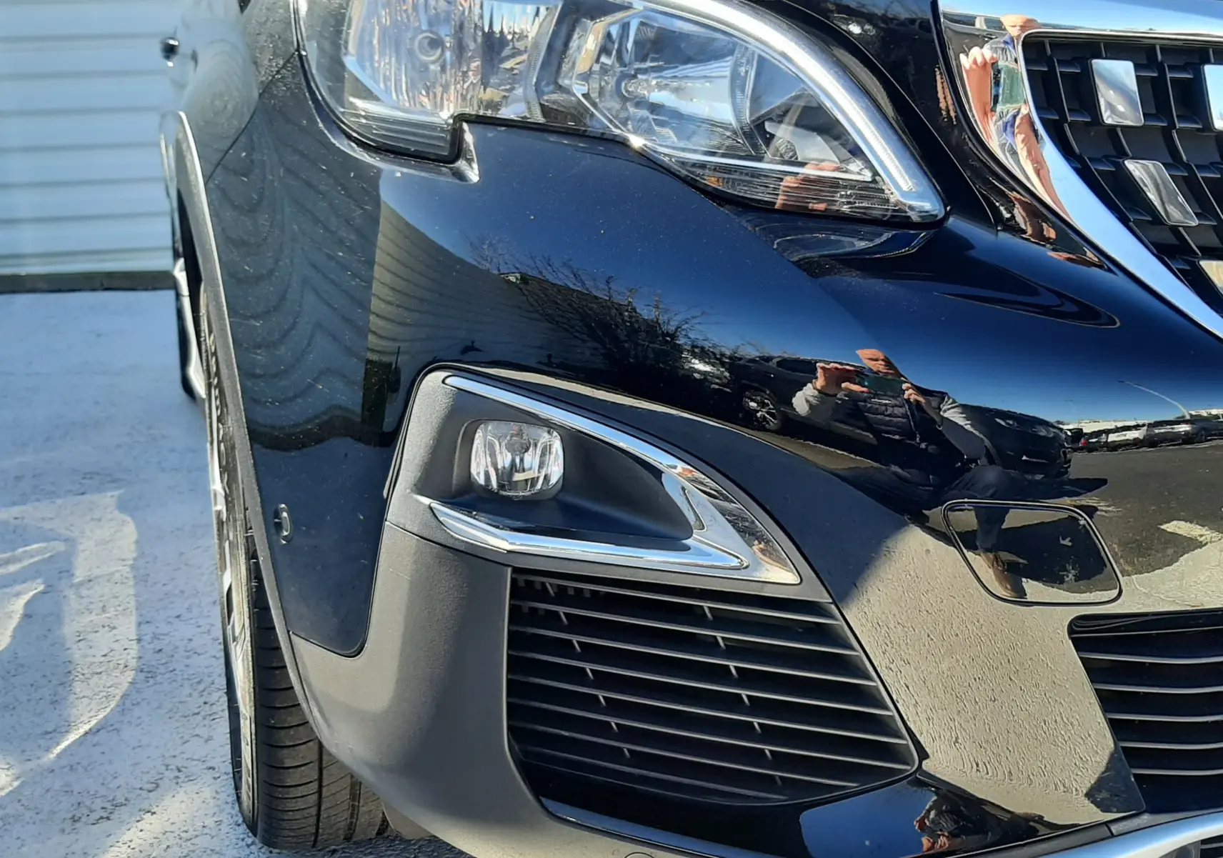 Gros plan sur l'avant droit noir brillant du Peugeot 3008 1.2 PureTech 130ch Allure avec phares et calandre chromée.
