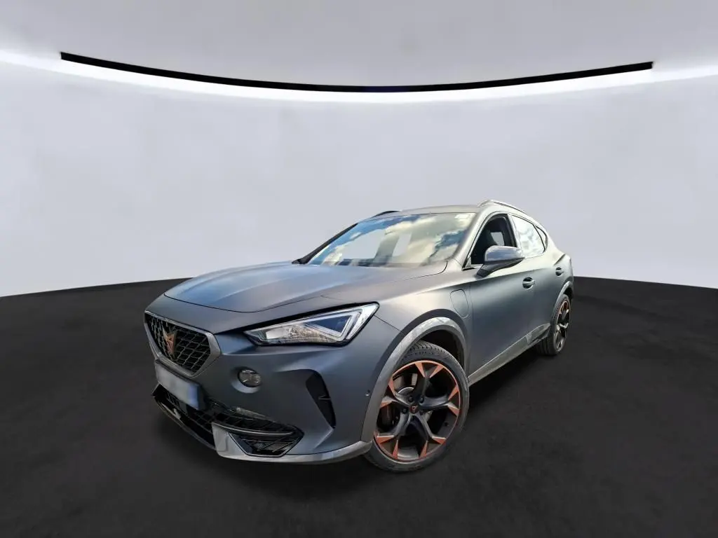 SUV CUPRA Formentor gris foncé mat en 3/4 avant droit, avec jantes noires et détails cuivrés, dans un showroom intérieur.