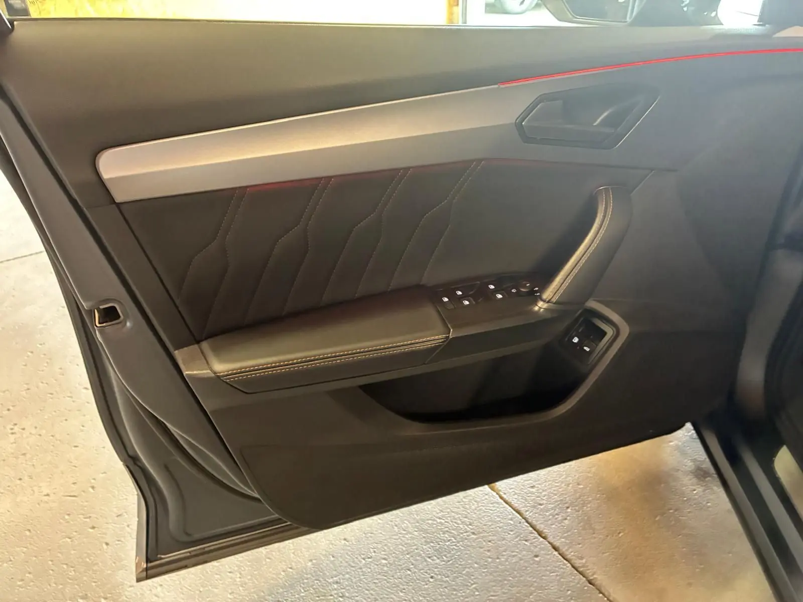 Vue intérieure côté gauche de la porte avant d'une CUPRA Formentor 1.4 E-HYBRID 2024 avec garniture noire et surpiqûres contrastantes.