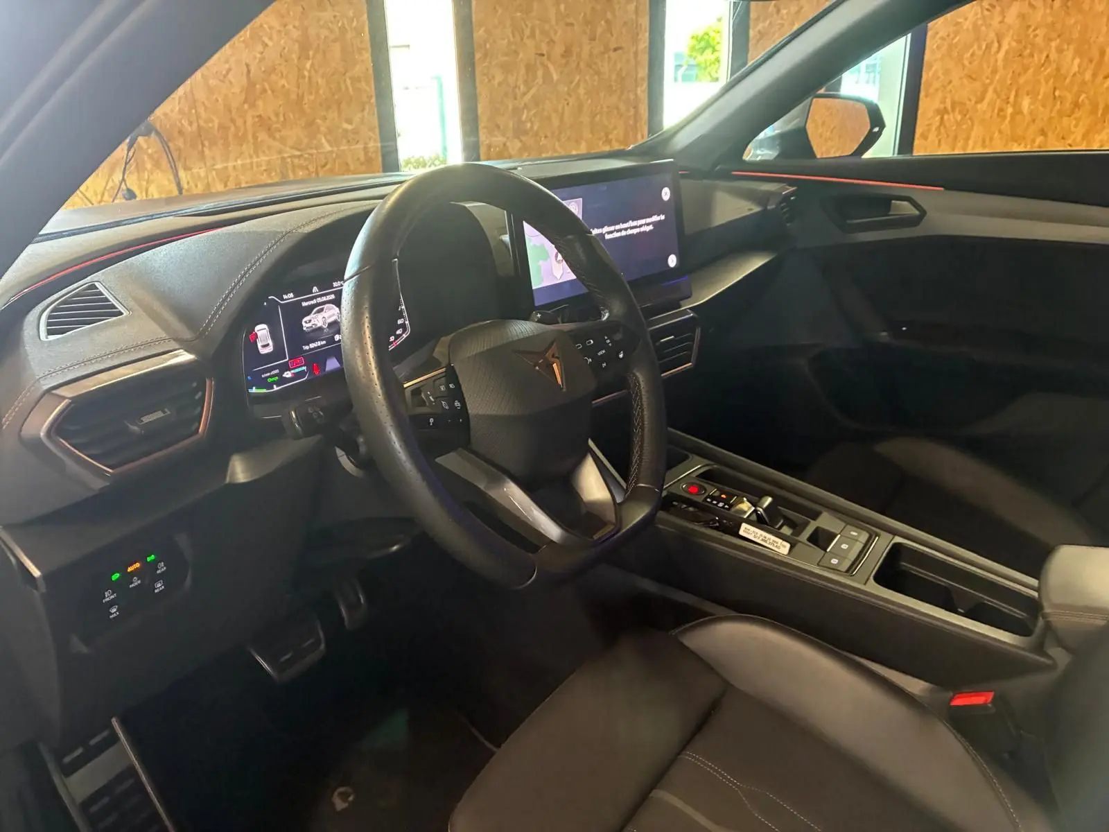 Vue intérieure côté conducteur de la CUPRA Formentor 1.4 E-HYBRID 2024, tableau de bord et volant noirs avec touches modernes.