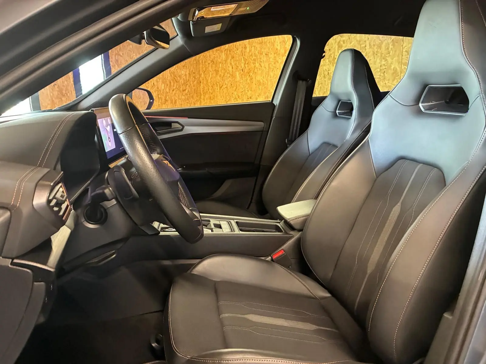 Intérieur avant de la CUPRA Formentor 1.4 E-HYBRID 2024, vue côté conducteur, sièges sport noirs avec surpiqûres contrastées.