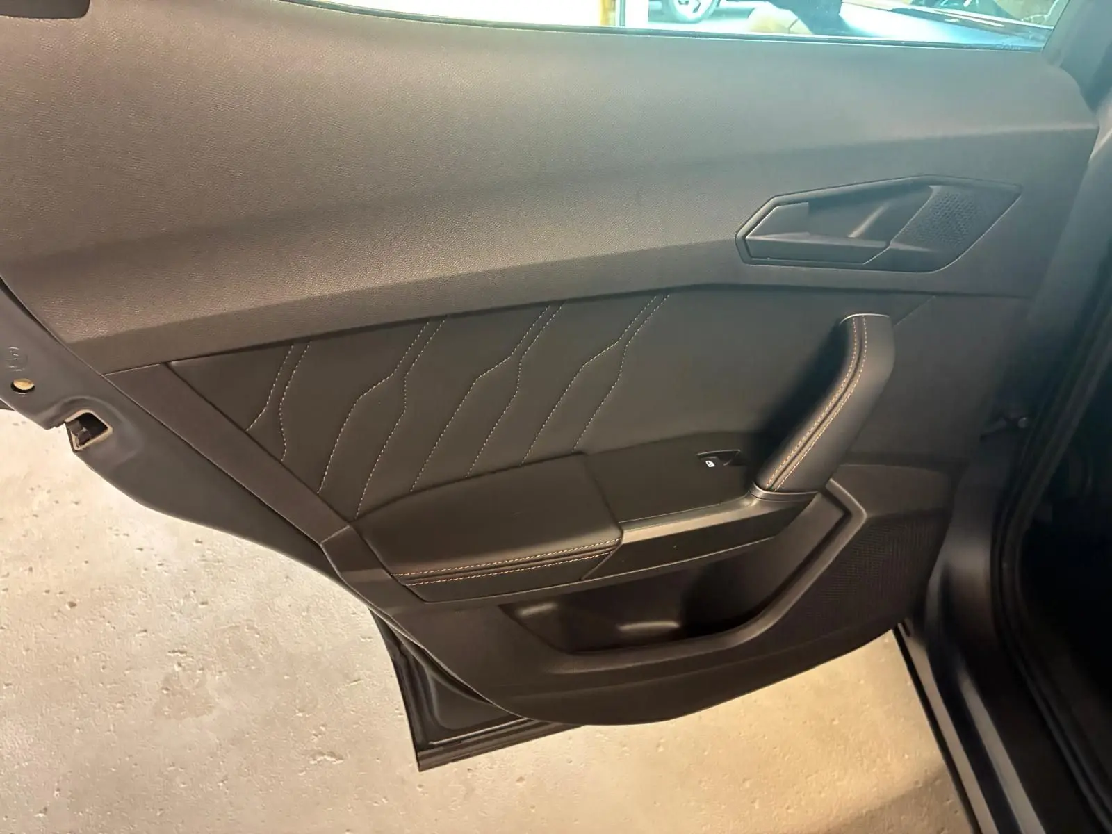 Vue rapprochée de la porte intérieure côté gauche du CUPRA Formentor 1.4 E-HYBRID 2024 avec surpiqûres et poignée noire.