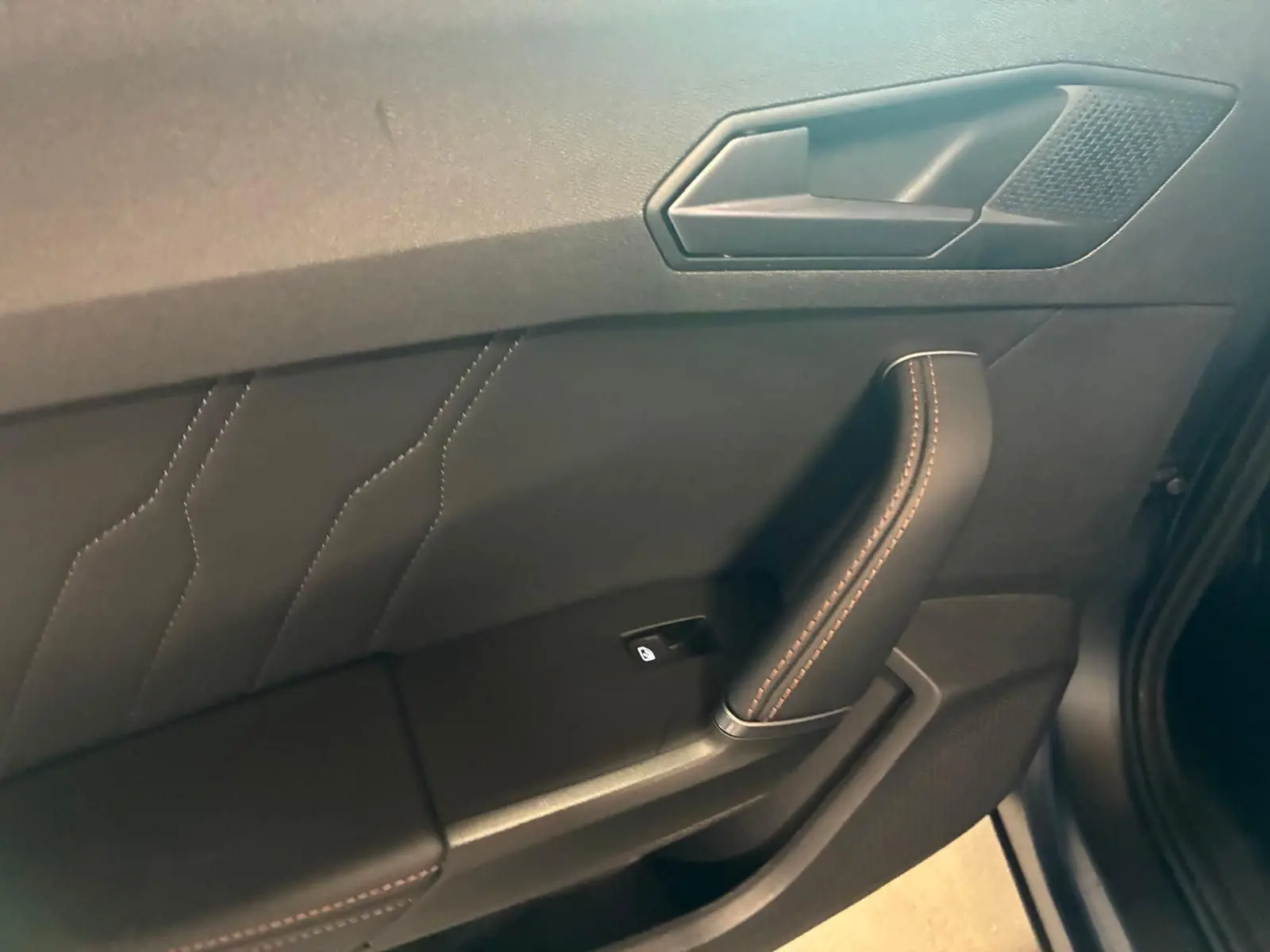 Détail de la porte côté conducteur du CUPRA Formentor 1.4 E-HYBRID 2024 avec surpiqûres orange sur cuir noir.