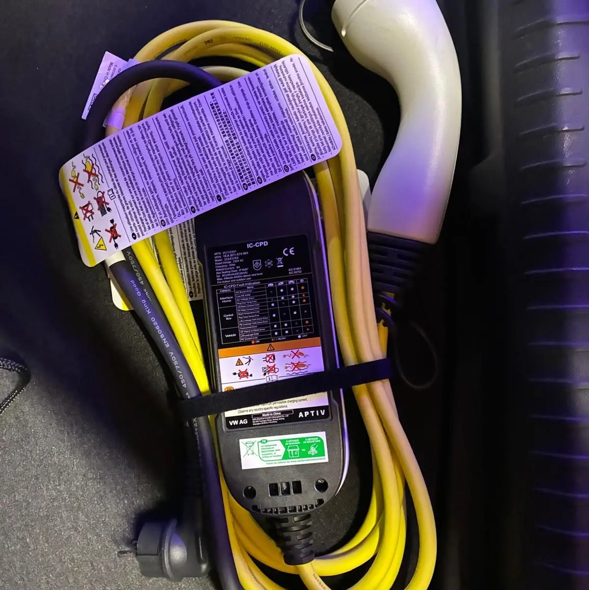 Câble de recharge jaune et noir pour CUPRA Formentor 1.4 E-HYBRID 245 DSG6 VZ, posé dans le coffre noir.