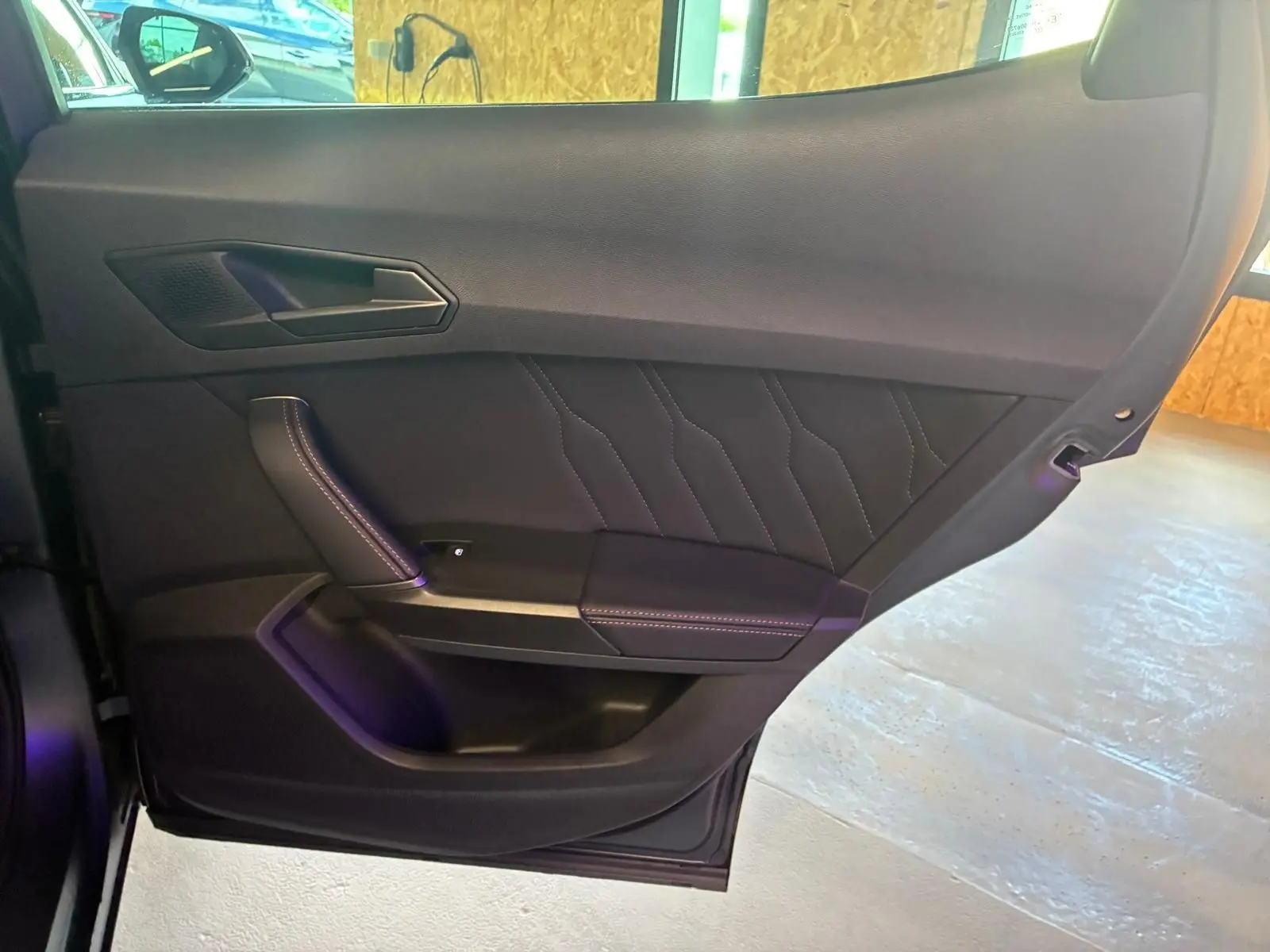 Vue intérieure côté gauche de la porte arrière d’une CUPRA Formentor gris foncé mat avec surpiqûres décoratives.
