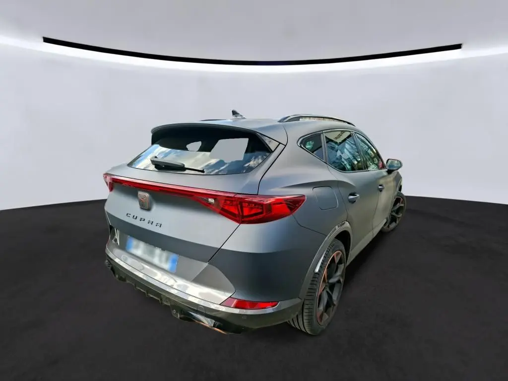 Vue 3/4 arrière droite du CUPRA Formentor gris foncé mat avec feux arrière allumés et jantes noires distinctives.
