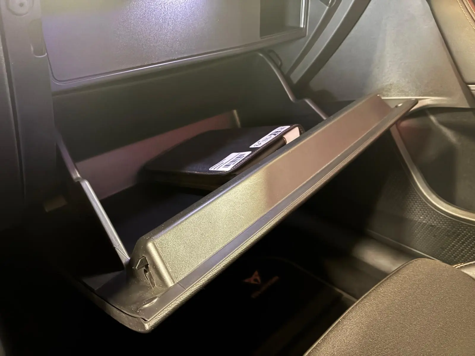Vue intérieure du vide-poche passager ouvert d'une CUPRA Formentor 1.4 E-HYBRID 2024 avec carnet de bord visible.
