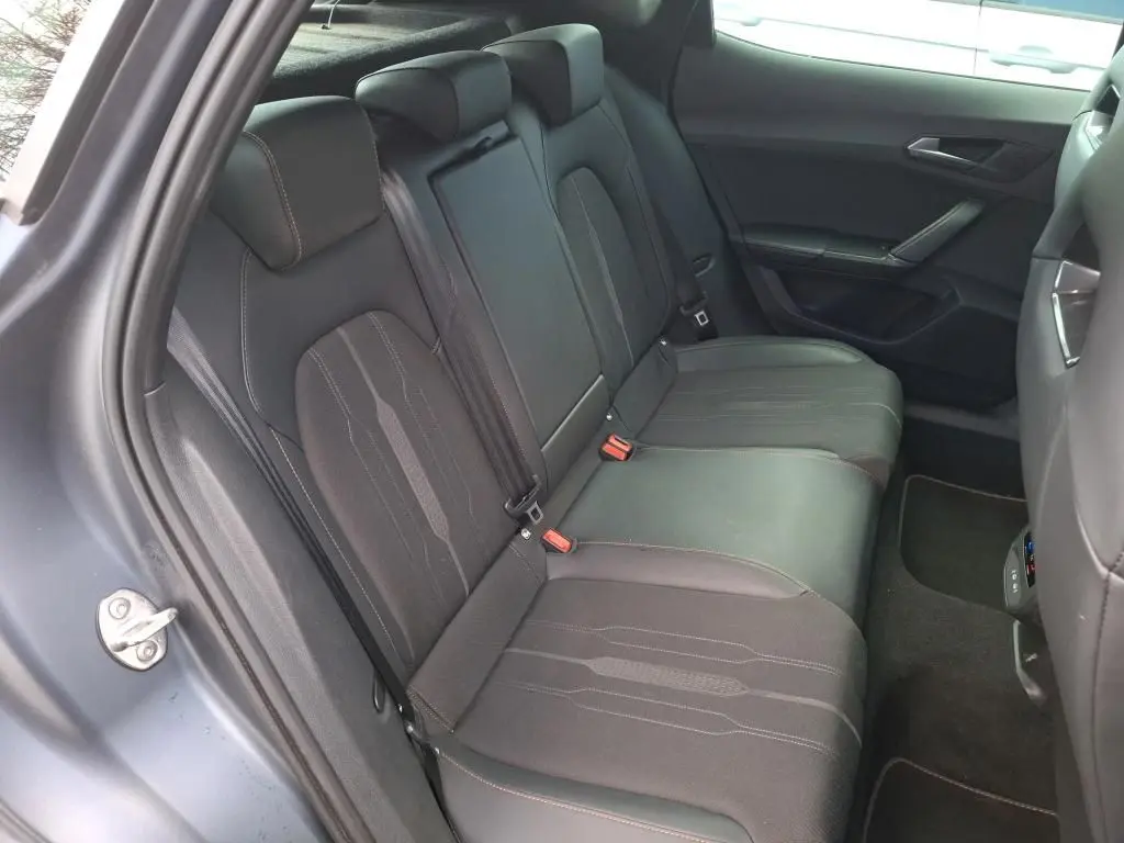 Vue 3/4 arrière droite d’un CUPRA Formentor 1.4 E-HYBRID gris foncé mat avec feux arrière allumés en intérieur.