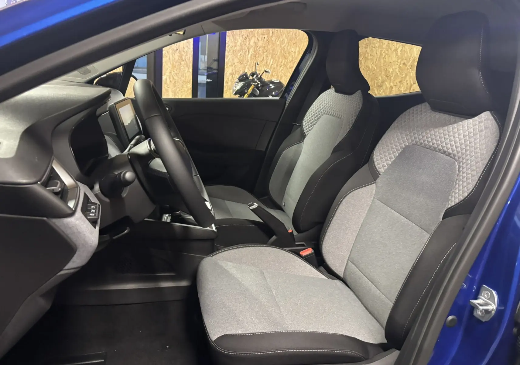 Vue intérieure côté conducteur de la Renault Clio TCE 90CH X-TRONIC Evolution 2024 bleu Iron avec sièges tissu gris noir.