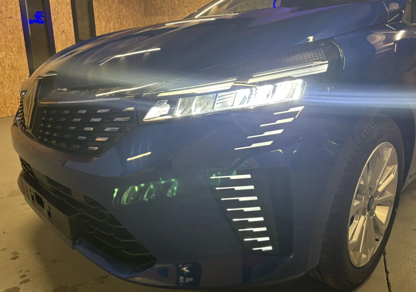 Vue 3/4 avant droit d'une Renault Clio TCe 90ch X-Tronic Evolution bleu Iron avec phares LED allumés et jantes alliage.