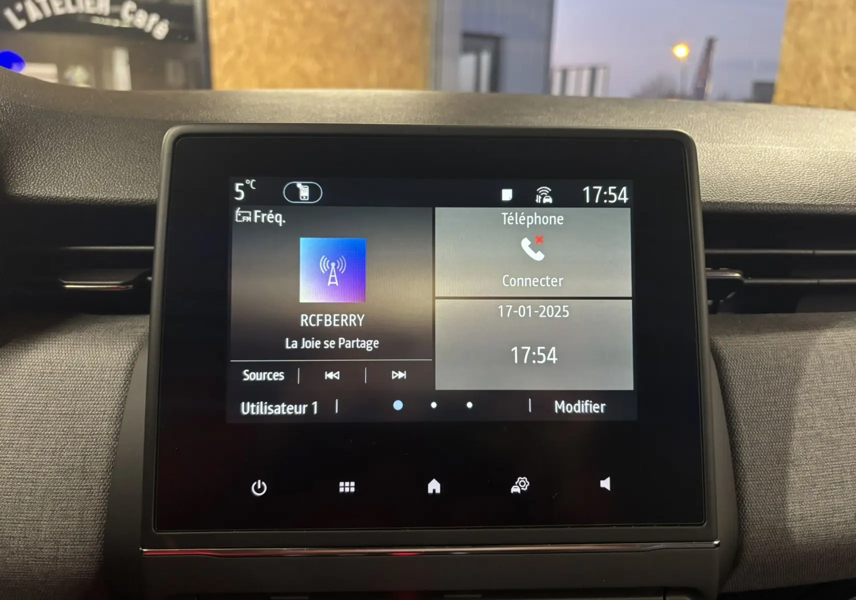 Écran tactile central de la Renault Clio 2024 affichant la radio et les options téléphone dans un intérieur gris noir.