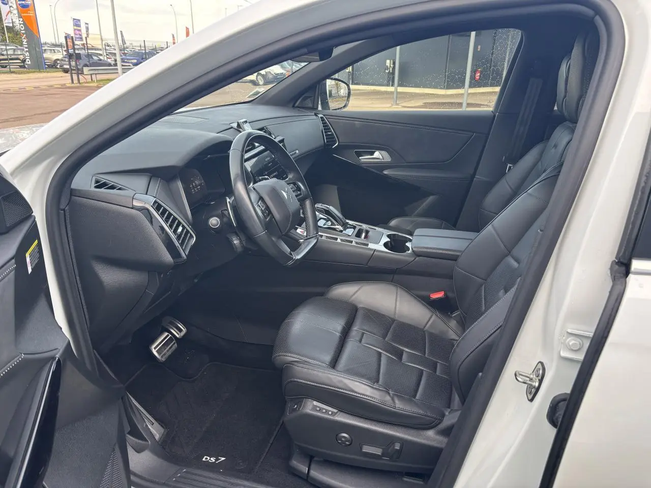 Intérieur côté conducteur du DS7 Crossback blanc 2021, sièges cuir noirs et tableau de bord moderne.