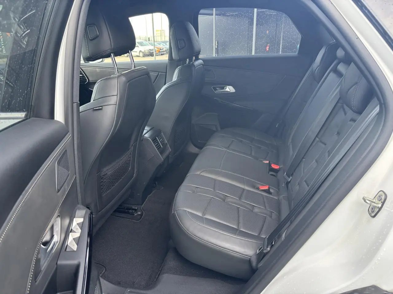 Vue côté gauche de l'habitacle arrière du DS7 Crossback blanc, avec sièges en cuir noir et finitions élégantes.