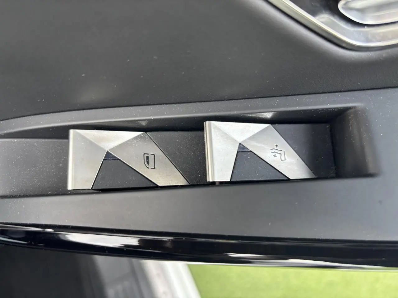 Boutons métalliques de commande des vitres sur la portière côté gauche d'un DS7 Crossback blanc de 2021.