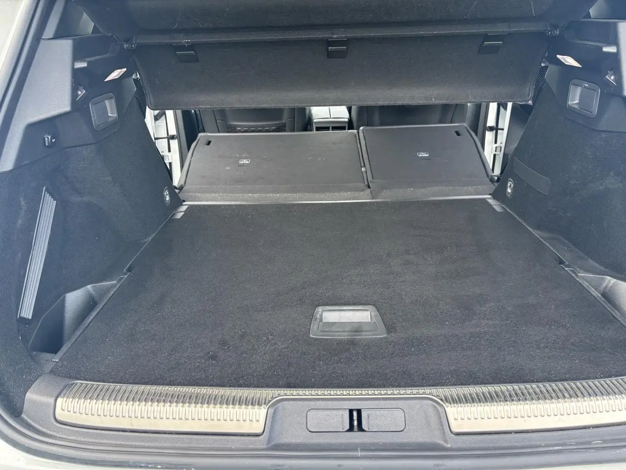 Coffre ouvert du DS7 Crossback blanc, banquette arrière rabattue, espace de chargement spacieux et revêtement noir.