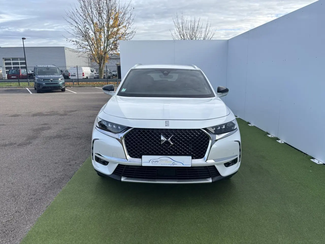 Vue frontale d'un DS7 Crossback blanc nacré avec calandre DS Wings chromée et phares LED distinctifs.