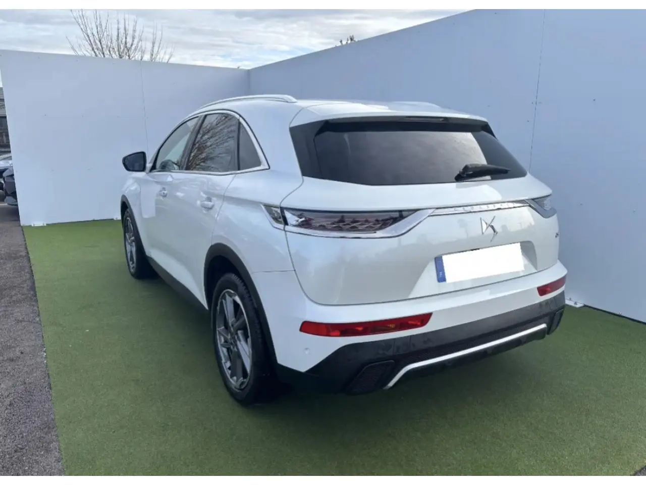 DS7 Crossback blanc nacré vu de 3/4 arrière droit avec vitres surteintées et feux arrière 3D à LED écailles