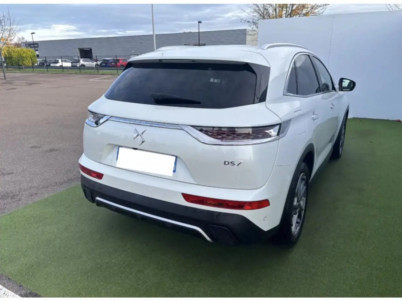 Vue 3/4 arrière droite d'un DS7 Crossback blanc nacré avec vitres arrière surteintées et feux arrière 3D écailles.