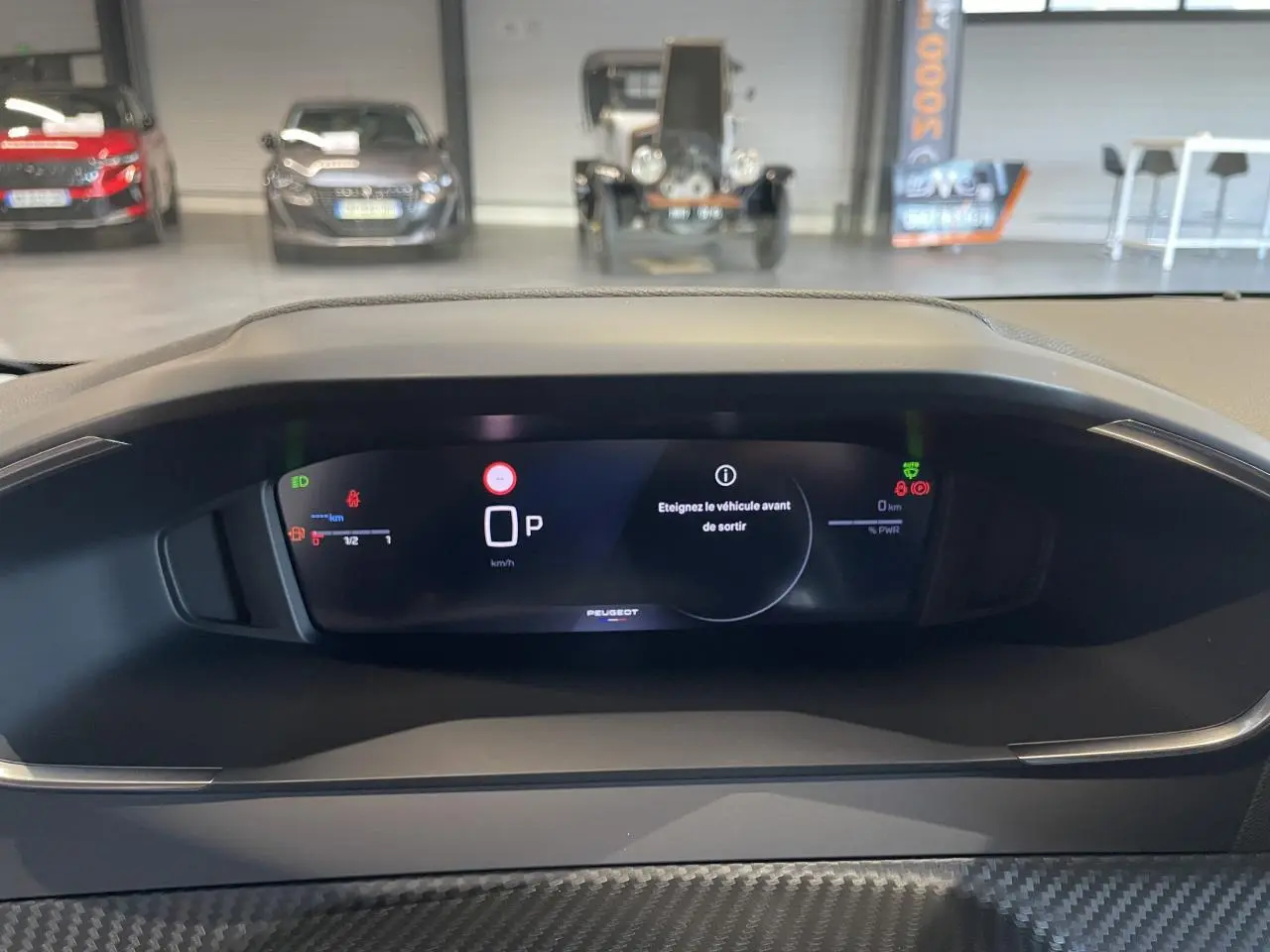 Vue rapprochée du tableau de bord numérique de la Peugeot 208 noire, affichant le mode parking et alertes.