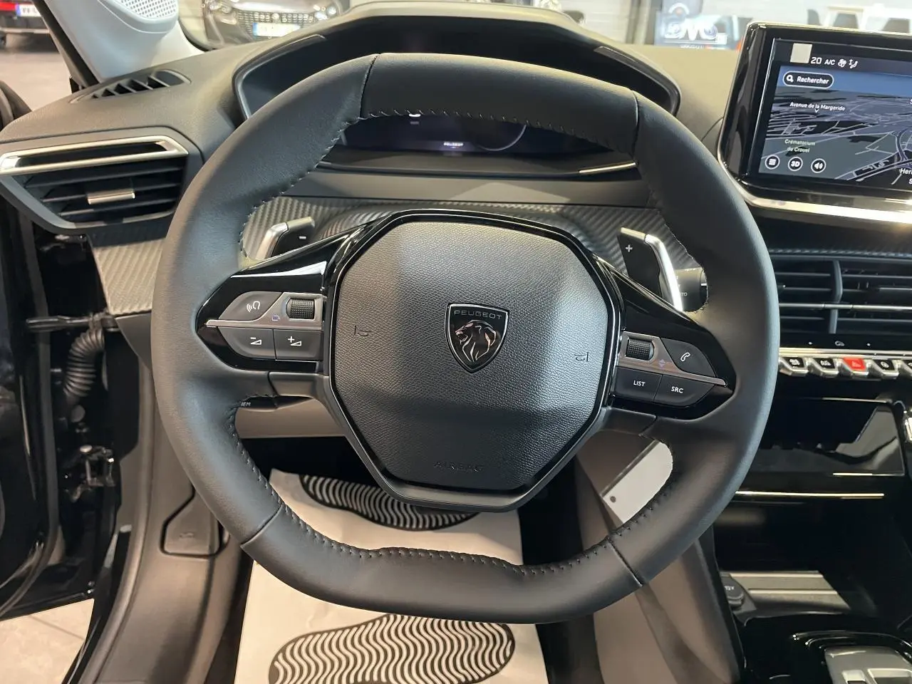 Volant cuir noir de Peugeot 208 2025 en vue frontale avec commandes intégrées et tableau de bord numérique.