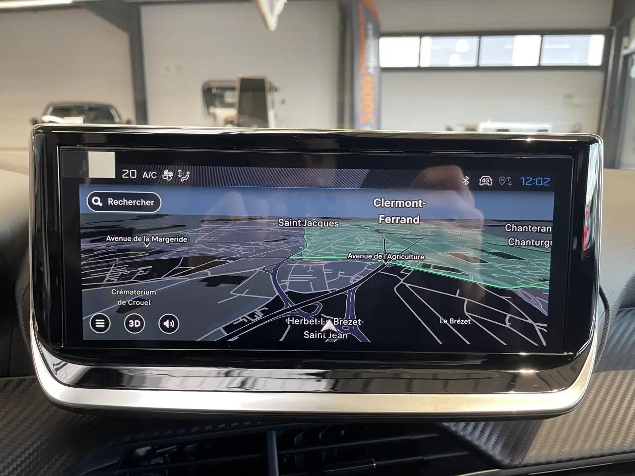 Écran tactile du système de navigation Peugeot 208 2025 affichant une carte en mode 3D, intérieur noir.