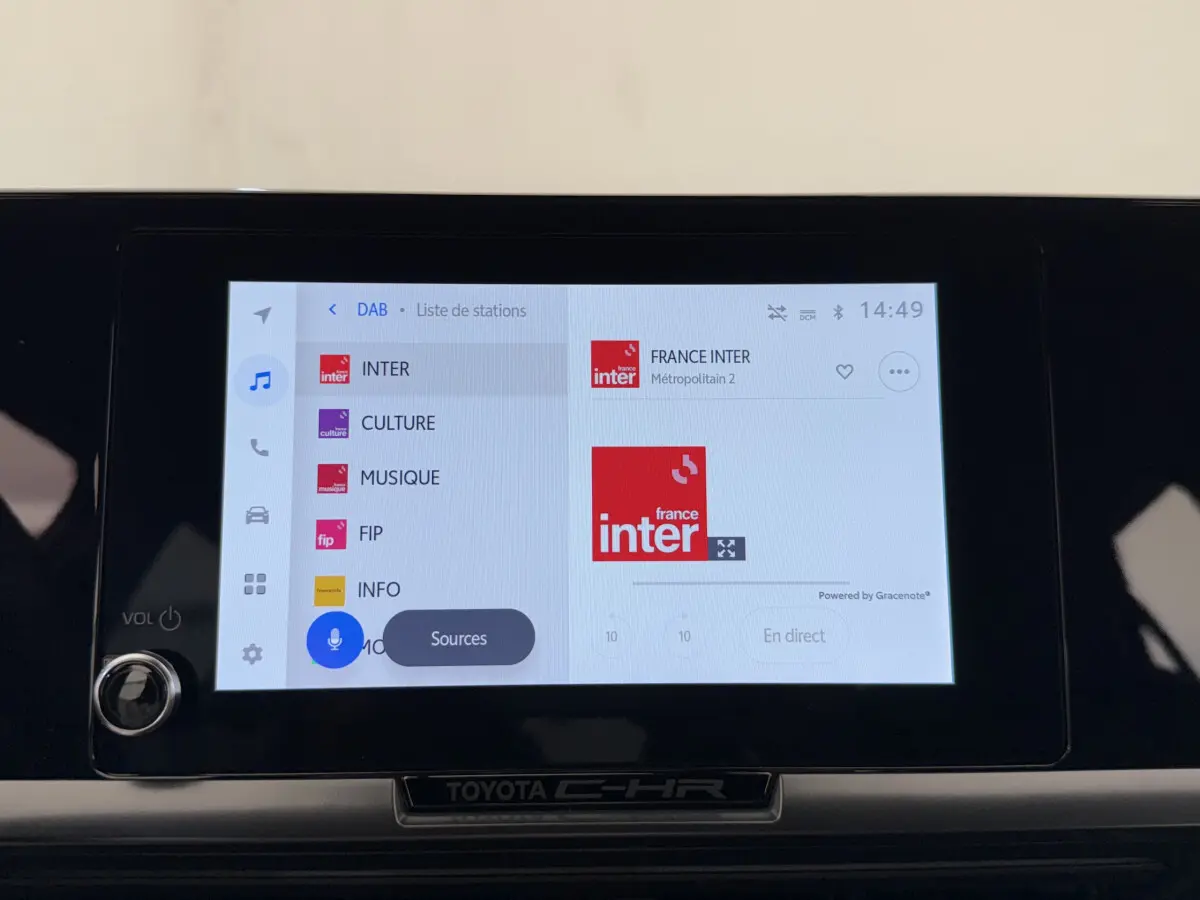 Écran tactile central du Toyota C-HR blanc 2024 affichant la liste des stations radio en mode DAB.