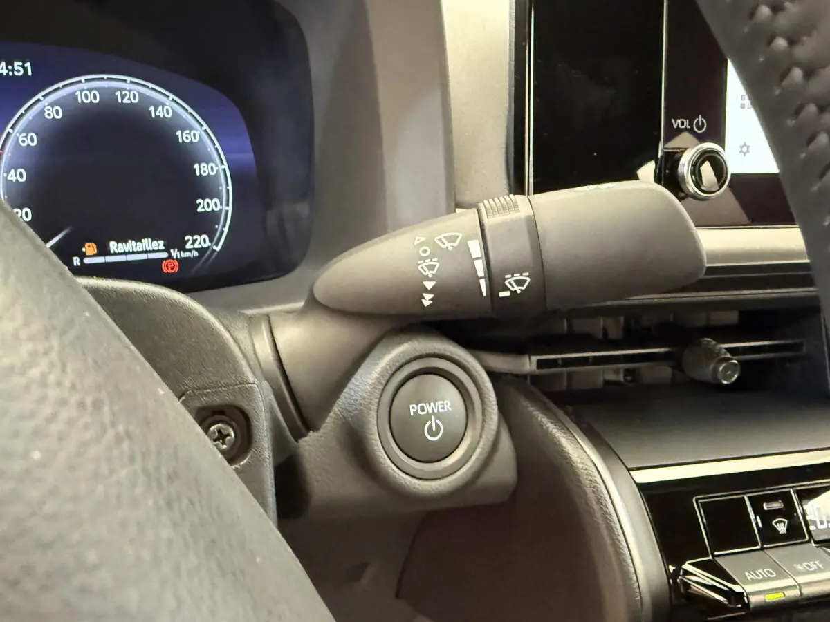 Gros plan intérieur sur le bouton Power et le combiné d'instruments numérique du Toyota C-HR 1.8 Hybride 2024.