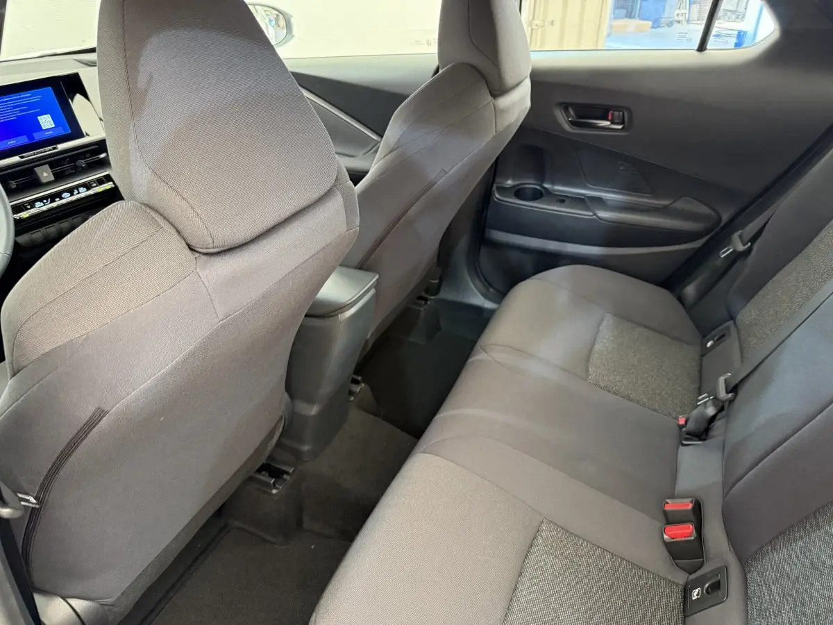 Vue intérieure arrière côté droit du Toyota C-HR 1.8 Hybride 140 Dynamic, sièges tissu gris et console centrale noire.