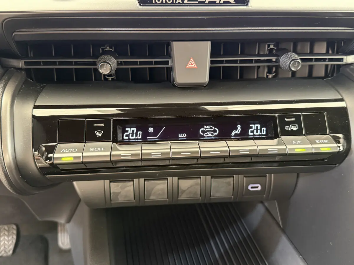 Gros plan sur la console centrale du Toyota C-HR blanc 2024, affichant la climatisation digitale à deux zones.