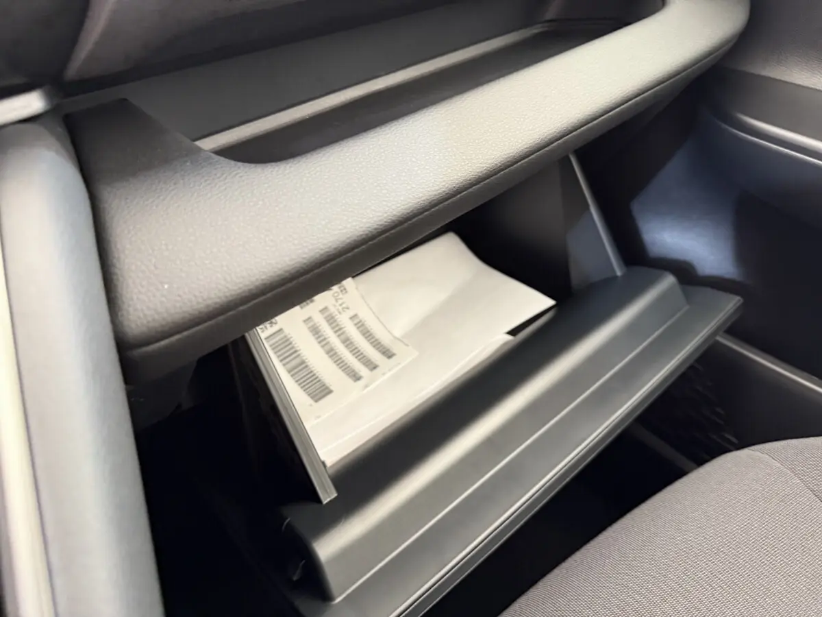 Intérieur du Toyota C-HR 1.8 Hybride 2024 en vue rapprochée de la boîte à gants ouverte avec documents visibles.