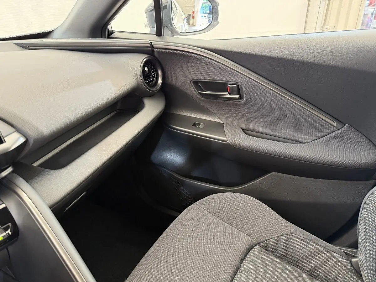 Vue intérieure côté passager du Toyota C-HR 1.8 Hybride 140 Dynamic 2024 avec sellerie grise et garnitures noires.