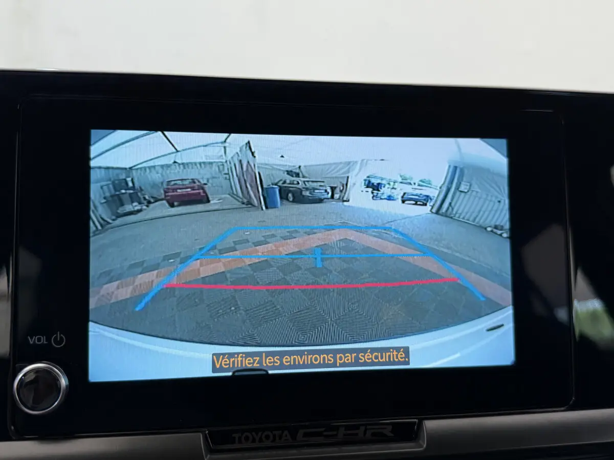 Vue caméra de recul du Toyota C-HR blanc 2024, affichée sur l'écran central avec guidage de trajectoire coloré.