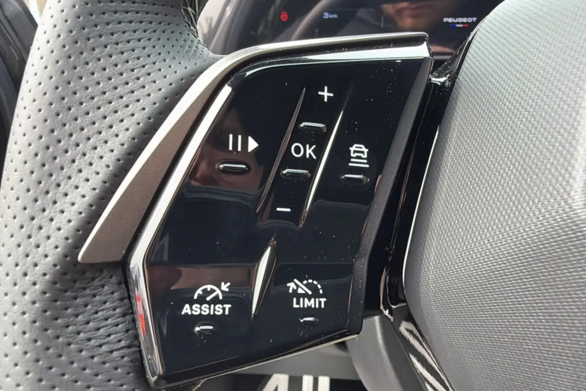 Gros plan sur les commandes du volant cuir perforé du Peugeot 3008 Hybrid gris titane, version GT Alcantara.