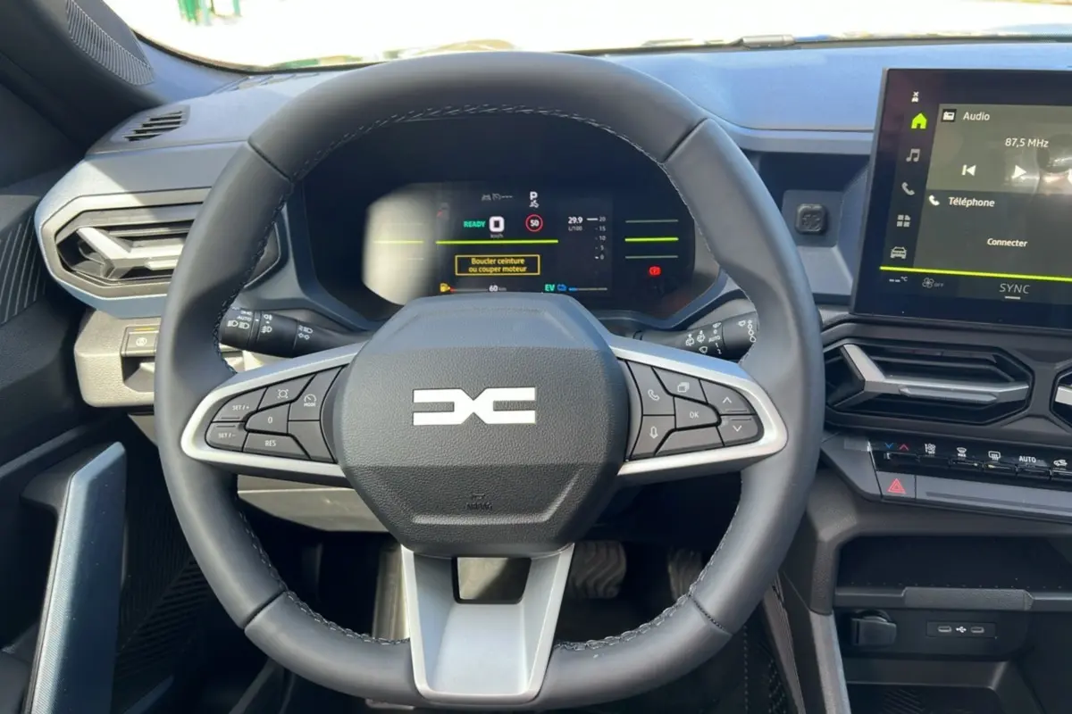 Vue intérieure centrée sur le volant cuir du Dacia Bigster Hybrid 155 Expression Plus avec tableau de bord digital et écran tactile.