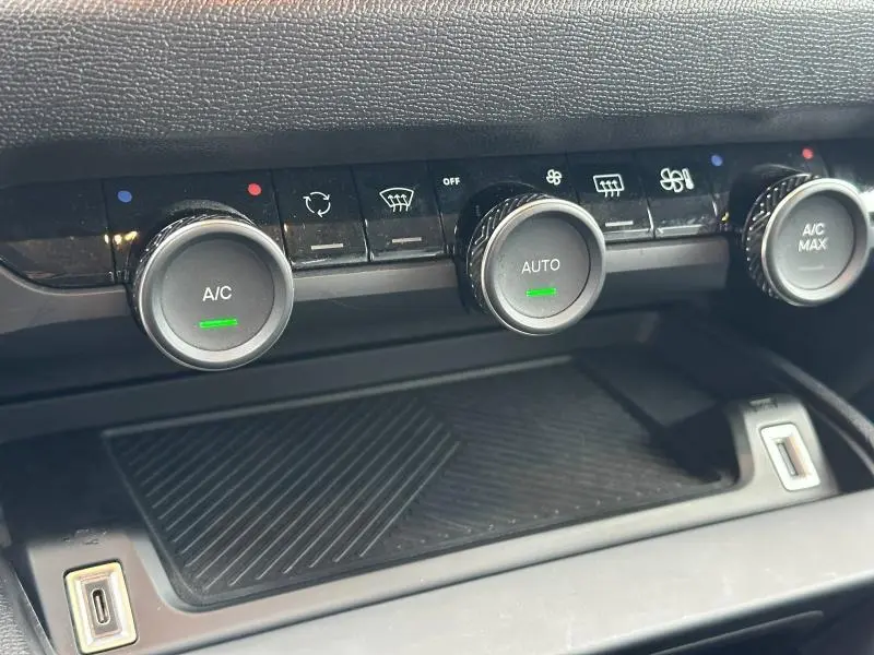 Gros plan sur les commandes de climatisation du Citroën C4 X 2025, boutons ronds avec réglages A/C et Auto, finition noire.