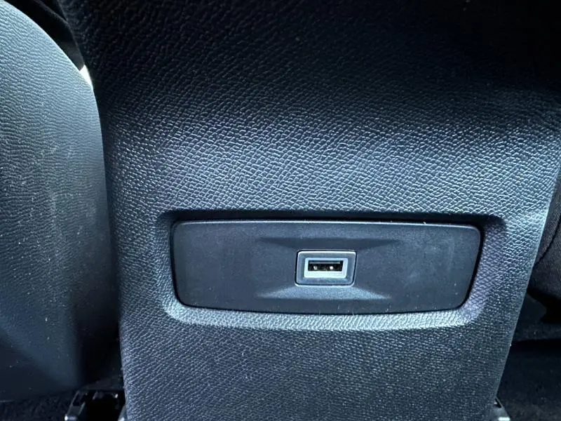 Prise USB intégrée en gros plan sur la console arrière du Citroën C4 X 1.2 Hybride 2025, intérieur noir texturé.