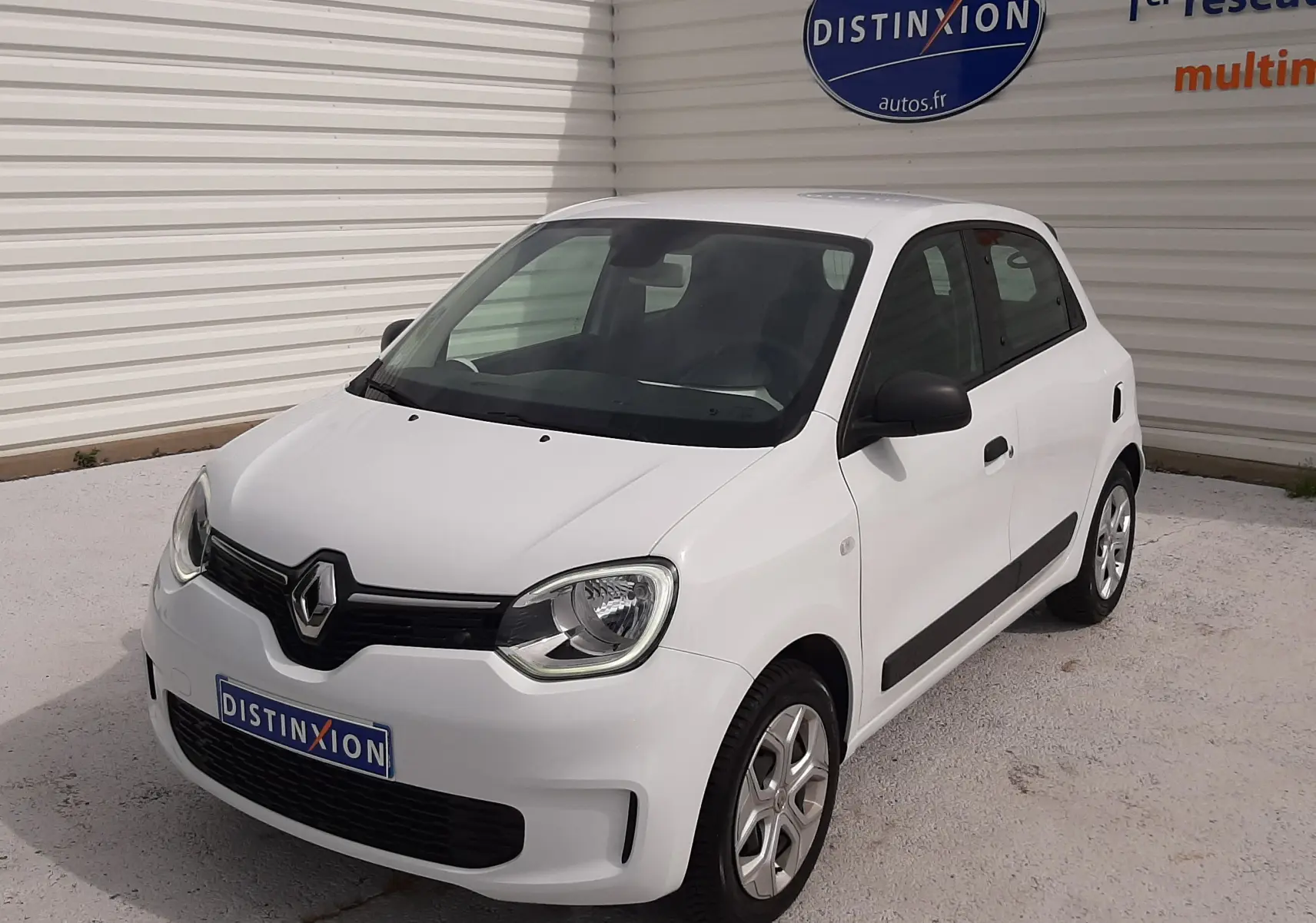 Renault Twingo III blanc cristal vue 3/4 avant droit, compacte 5 portes avec baguettes latérales noires.
