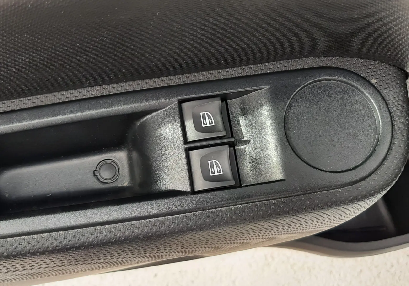 Gros plan sur les commandes de lève-vitres côté conducteur de la Renault Twingo III blanc cristal, finition tissu gris-noir.