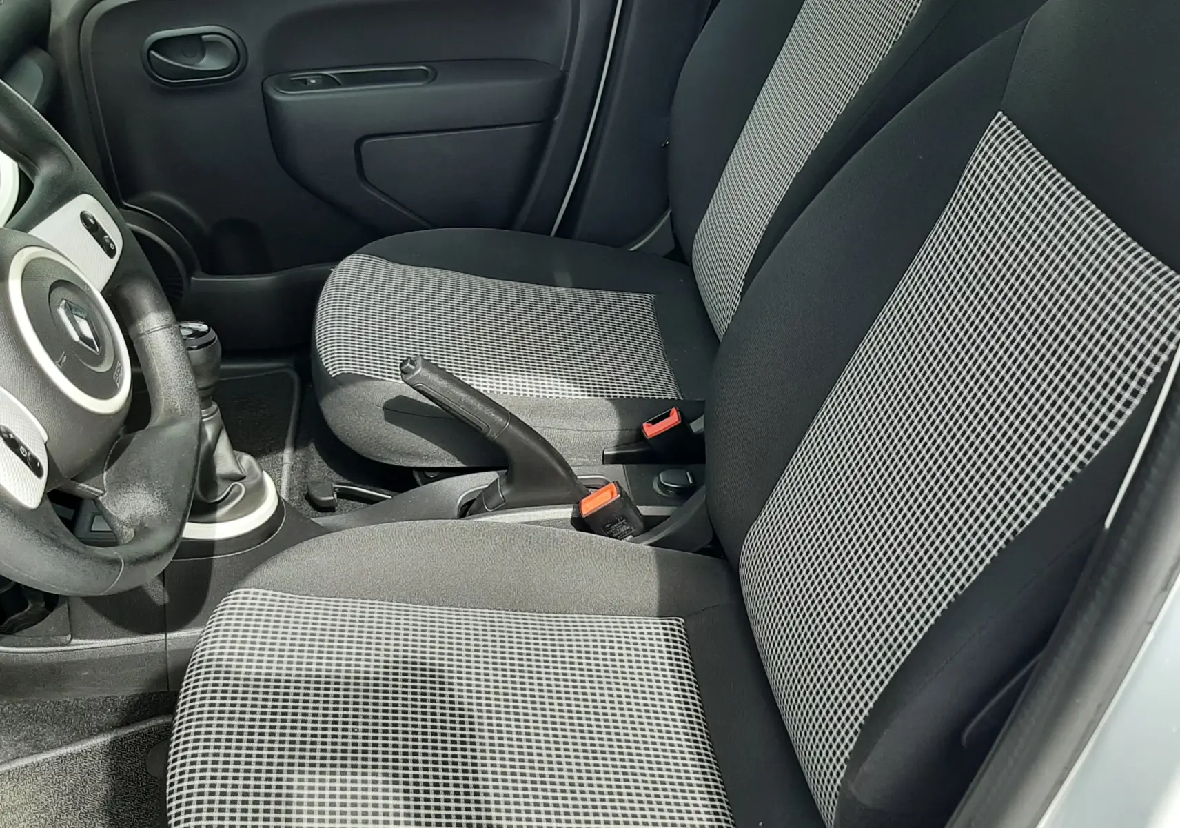 Vue intérieure côté gauche de la Renault Twingo III Life 2021, sièges tissu gris noir avec motifs à carreaux.