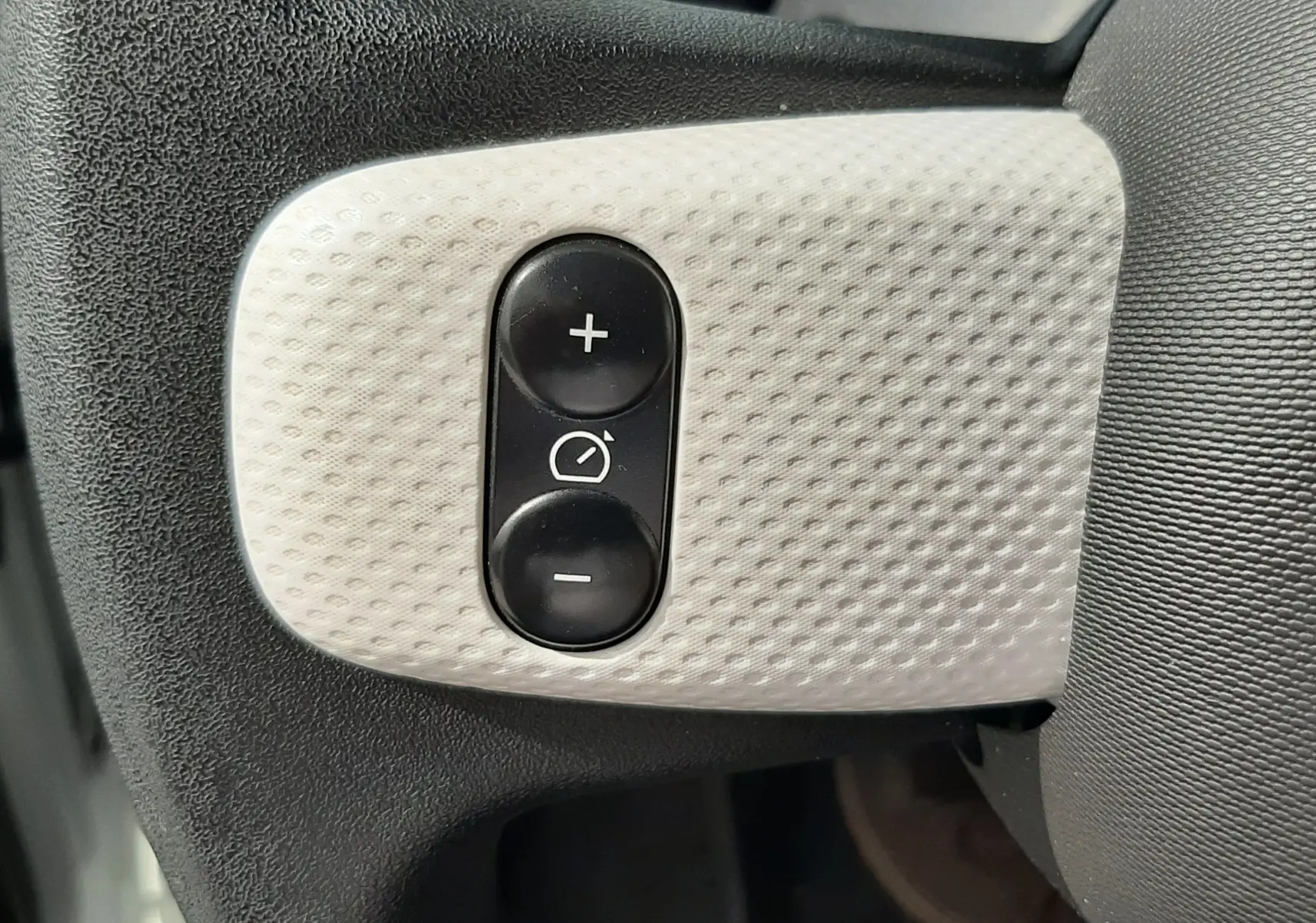 Gros plan sur les boutons de réglage des rétroviseurs sur le volant d’une Renault Twingo III blanc cristal.