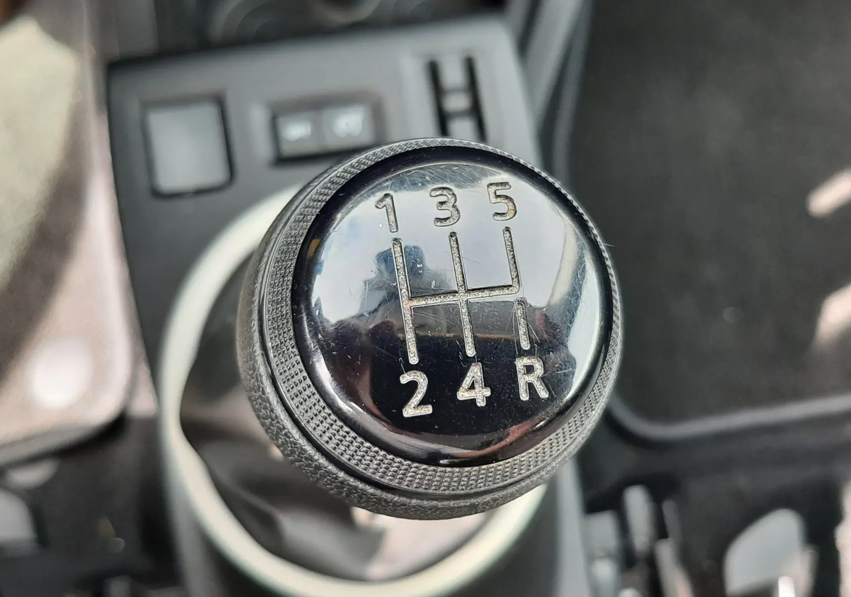 Gros plan sur le levier de vitesses manuel noir de la Renault Twingo III blanc cristal, avec marquages des rapports visibles.