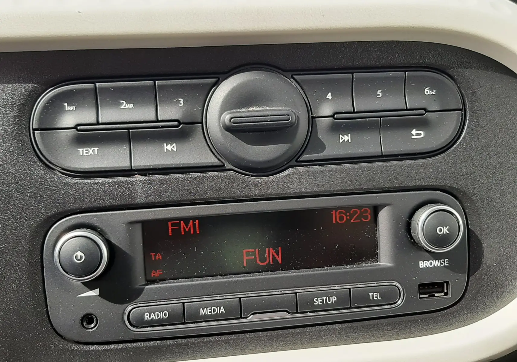Gros plan sur la console centrale noire et blanche du Renault Twingo III blanc cristal, avec écran radio affichant "FUN".